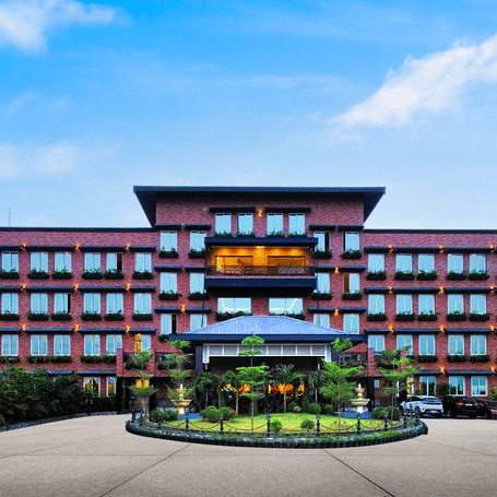 Exterior wide shot of the modern, multi-story MAYFAIR Purnea building under a bright blue sky.
