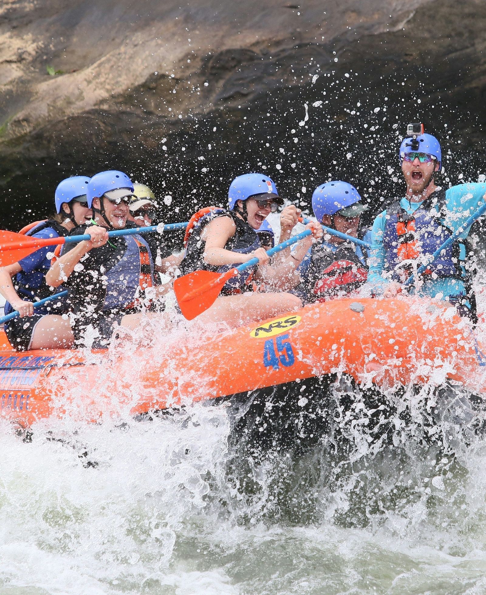 A group of people wearing helmets rafting through a river