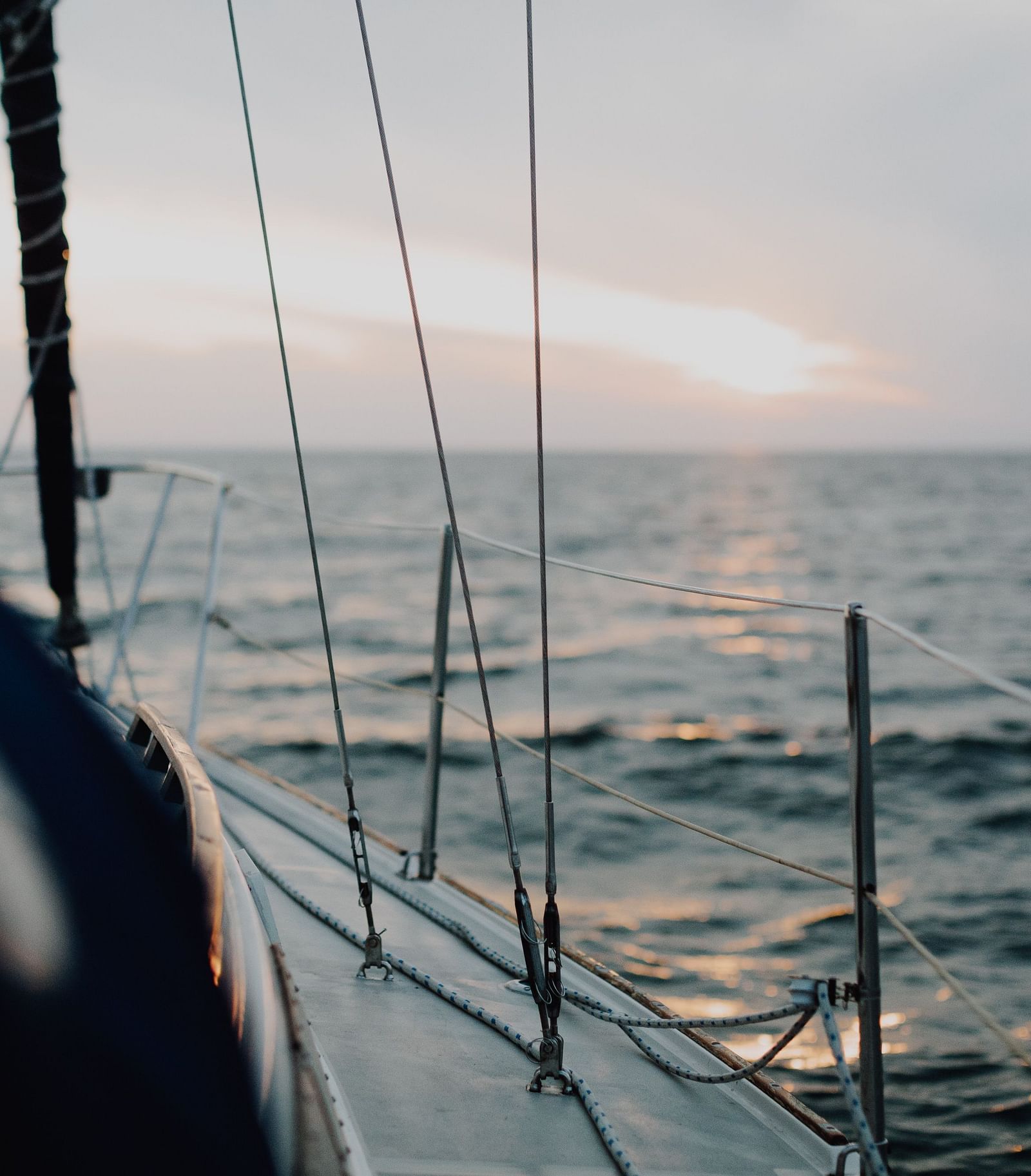 A close up shot of inside a boat of the vast ocean with the sun shining in the distance.