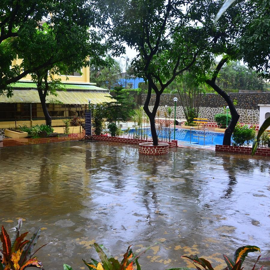view of the swimming pool and the outside area during monsoon - Zara's Resort
