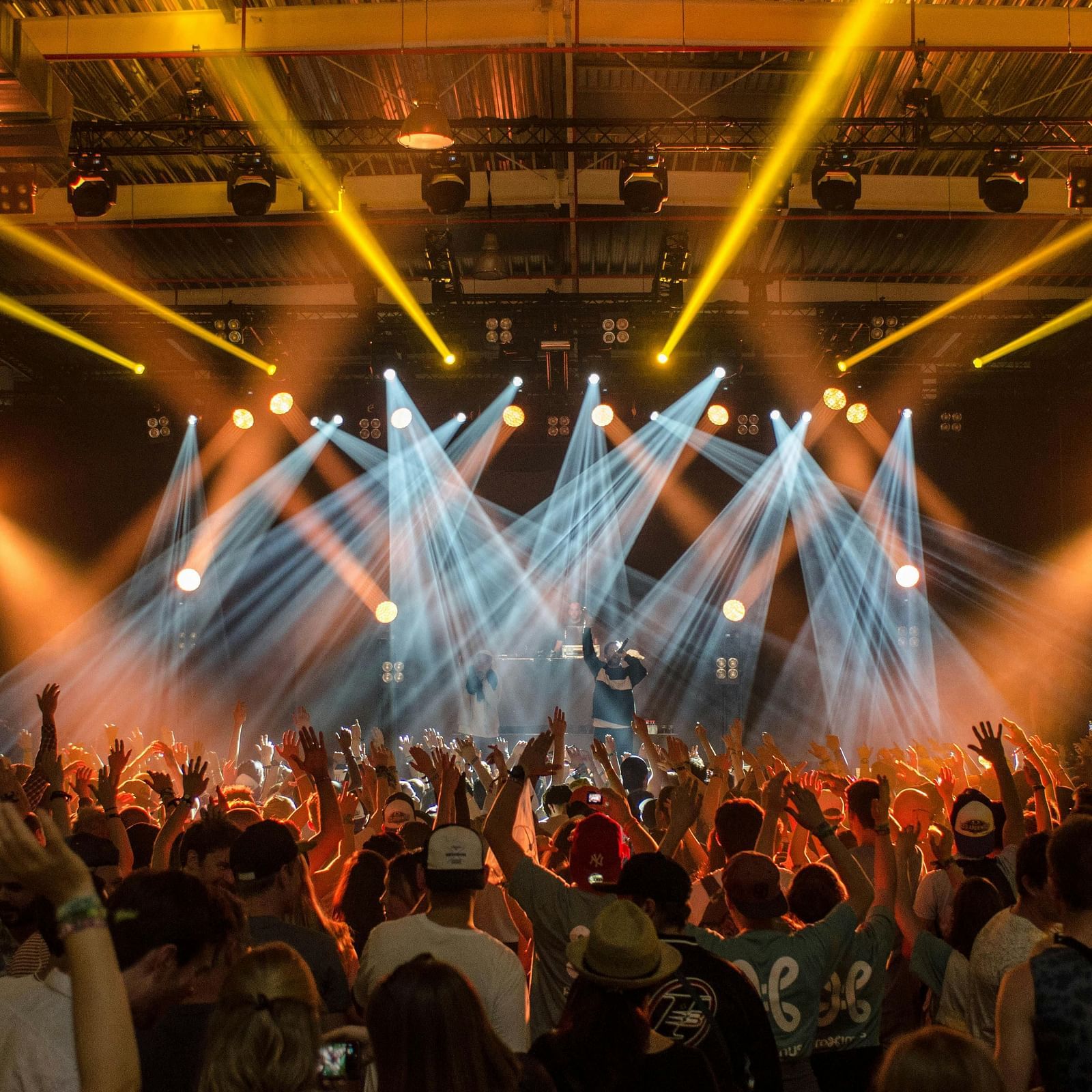 A wide view of people dancing at a concert with laser lights