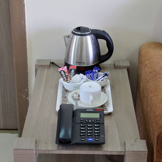 A picture of a kettle, coffee mugs, sachets and telephone on a table