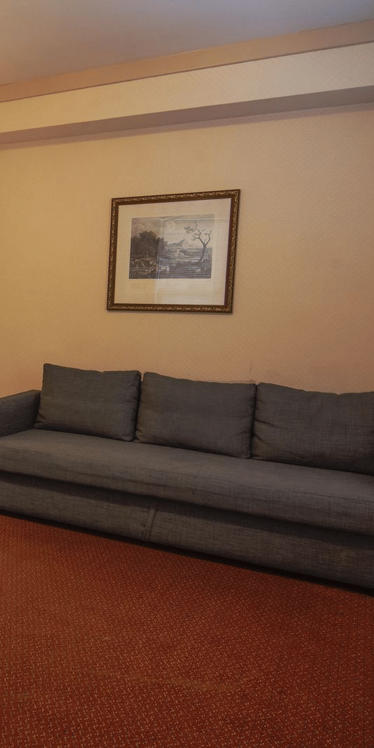 Spacious room at Night Hotel Broadway featuring a sofa, work desk, chair, lamp, and warm ambient lighting.