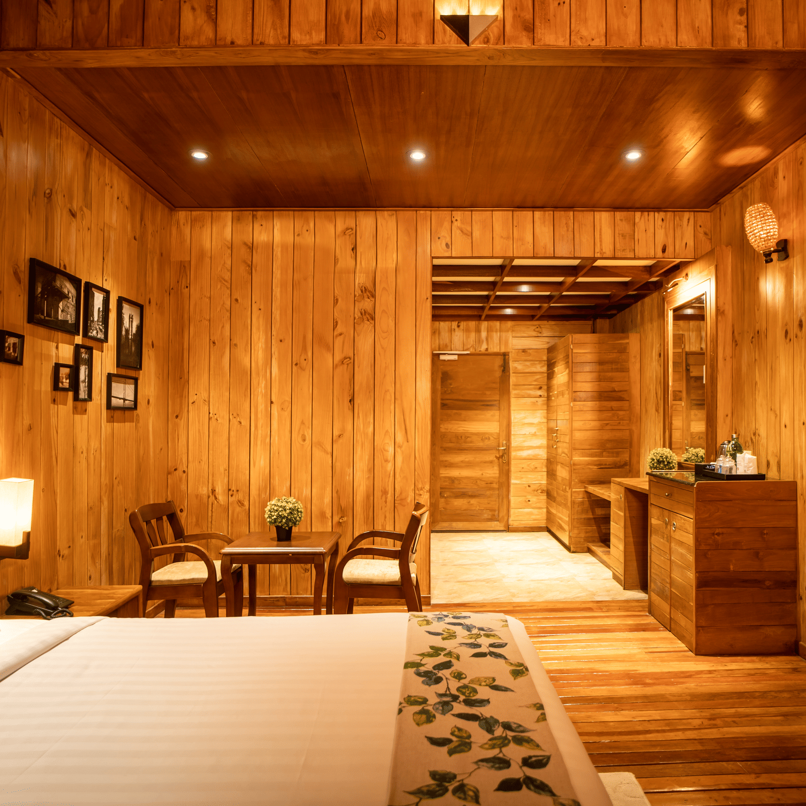 An image of a hotel room with a bed with blue pillows and illuminated by bright lights