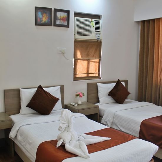 A room featuring well made twin beds, a/c and wall paintings - Maxxvalue Apartment Marol