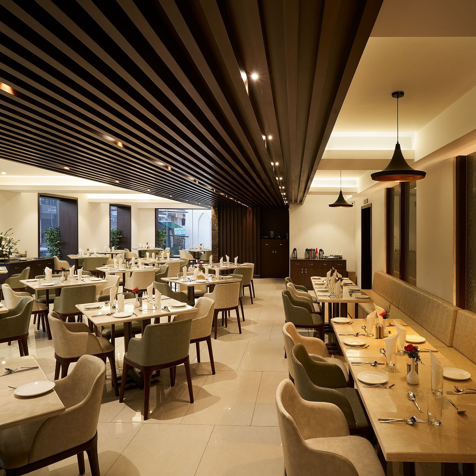Spacious dining area with tables and chairs on one side, and seats along the wall on the other at The Hamuse Hotel, Kodaikanal.