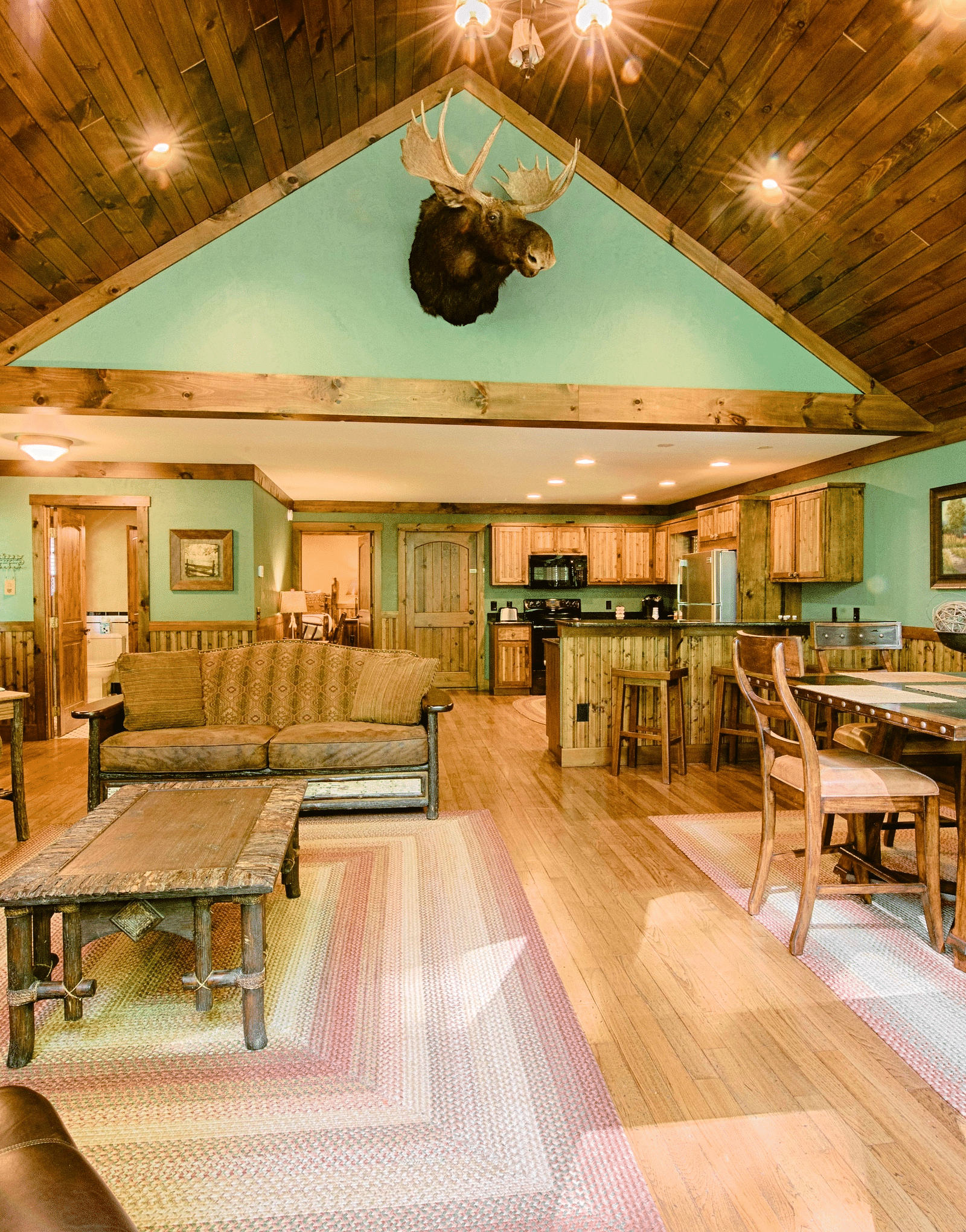 full view image of the living area with a seating area and a dining table along with a decorative stag head hanging above the room - Historic Tapoco Lodge