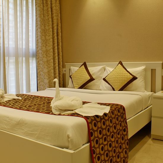 A room featuring a well decorated bed and a side drawer - Maxxvalue Apartment Powai