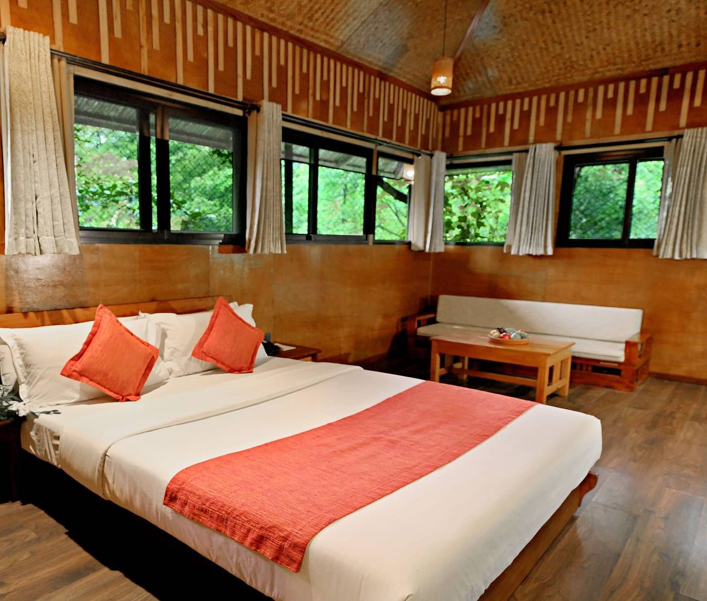 Room with multiple windows and a bed, offering lush forest views at Vythiri Resort, Wayanad