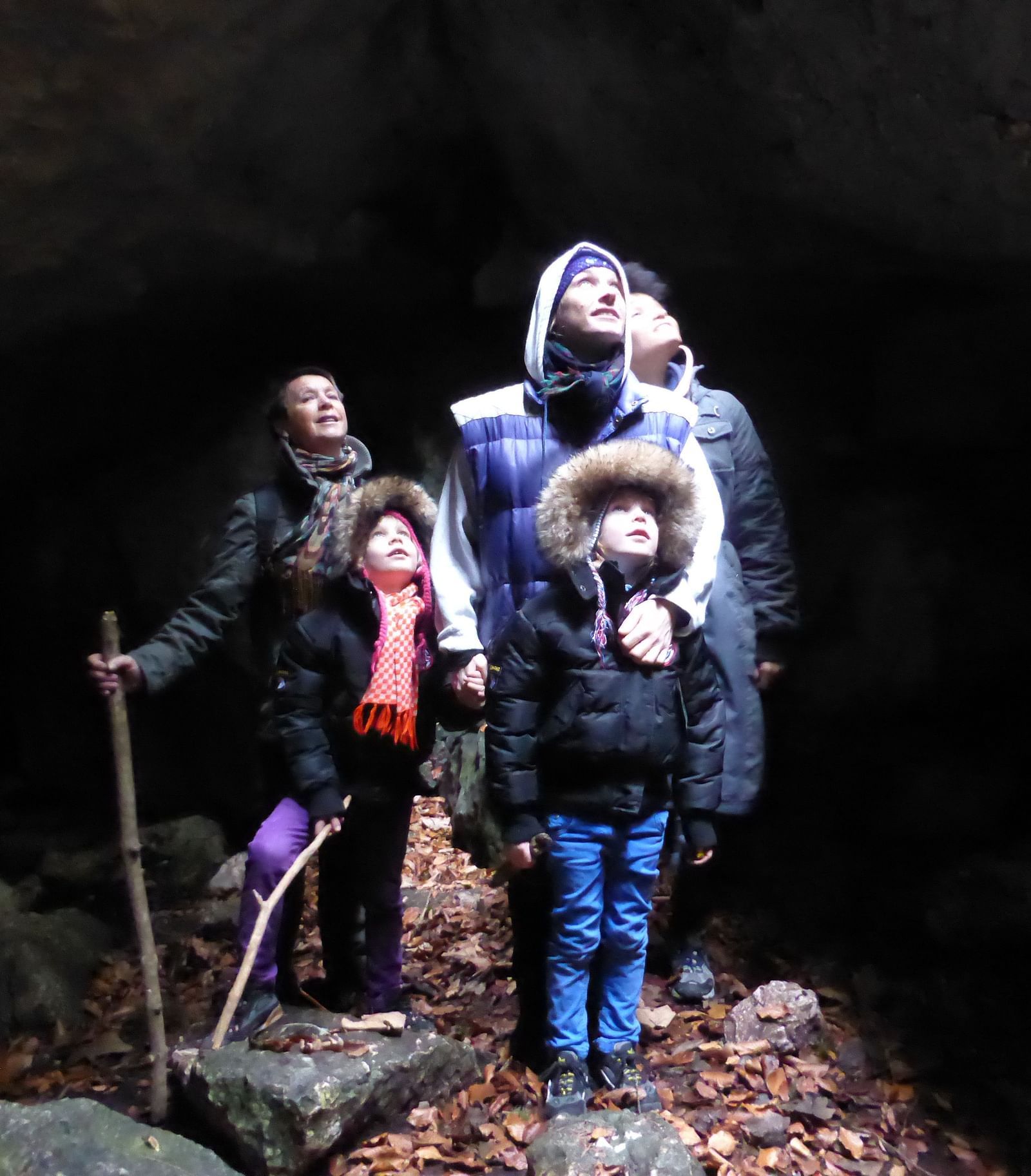 A family of five looking at the light while being in a cave and posing for a picture.