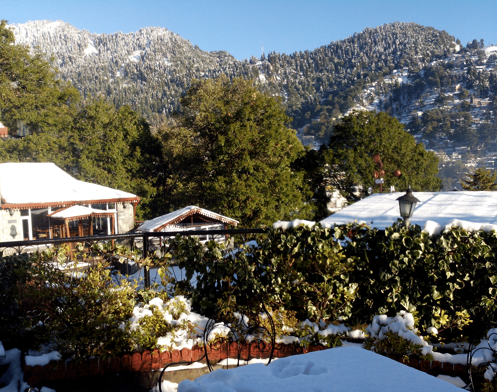 Image of outdoor seating, with a few buildins covered with snoew and snow-capped mountains in the background.