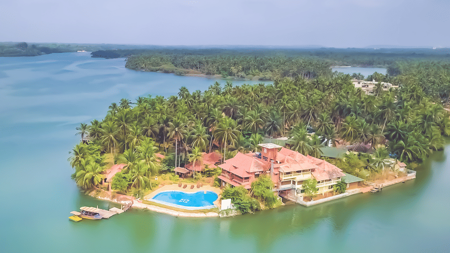 Aerial view of Paradise Lagoon Resort, Udupi, featuring a pool and water all around.