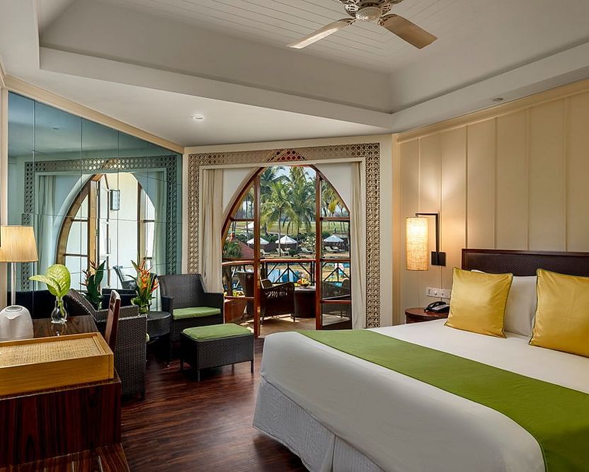 a double bed with a ceiling fan and a wall mounted tv inside Deluxe Room - Caravela Beach Resort Goa
