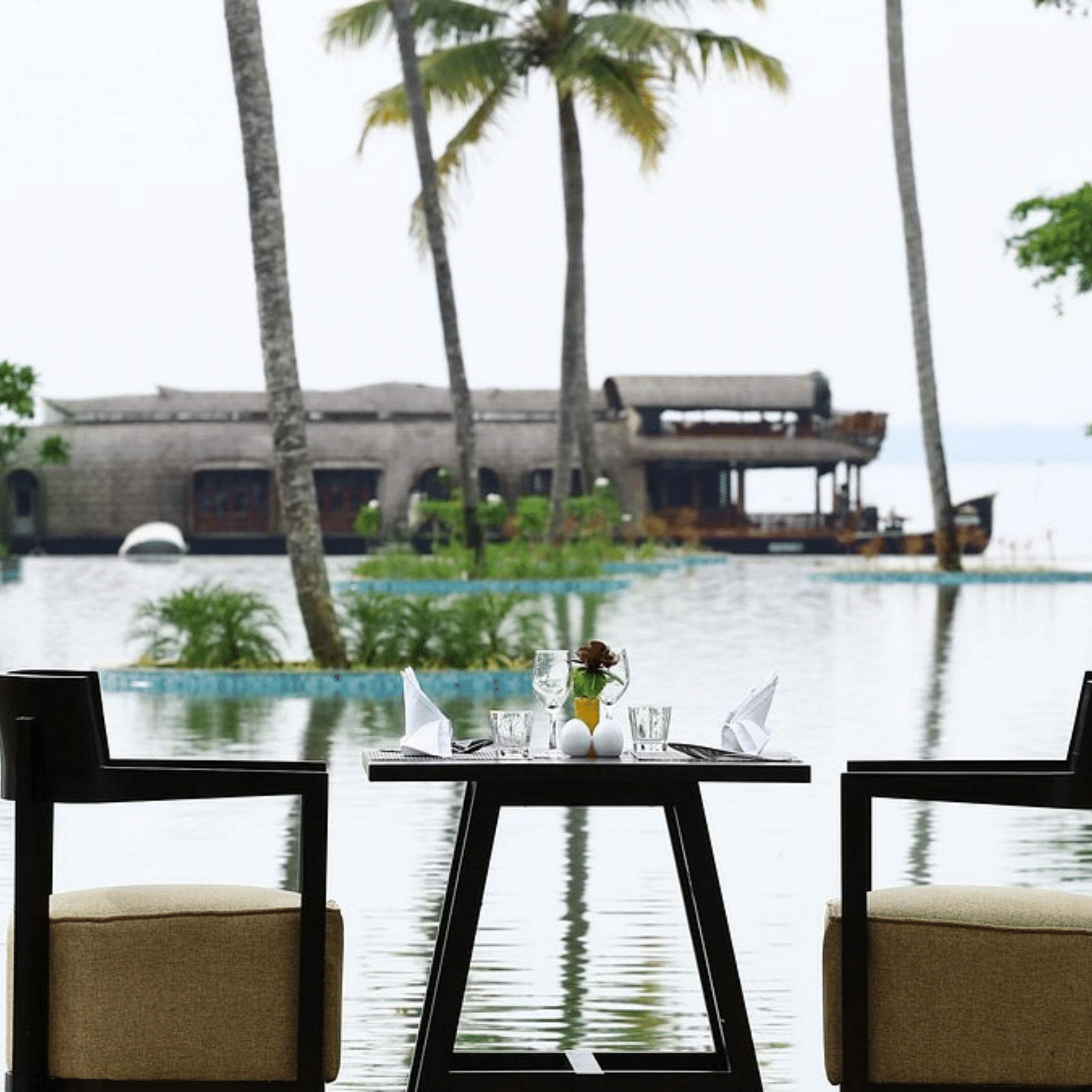 Seating arrangement in front of the pool with a coconut trees in view - Rhythm Kumarakom.