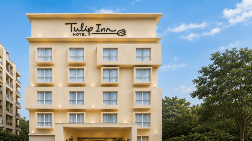 Daytime exterior shot of Tulip Inn, Hoodi Whitefield, Bengaluru, showing the building facade, a driveway, vehicles, and foliage.