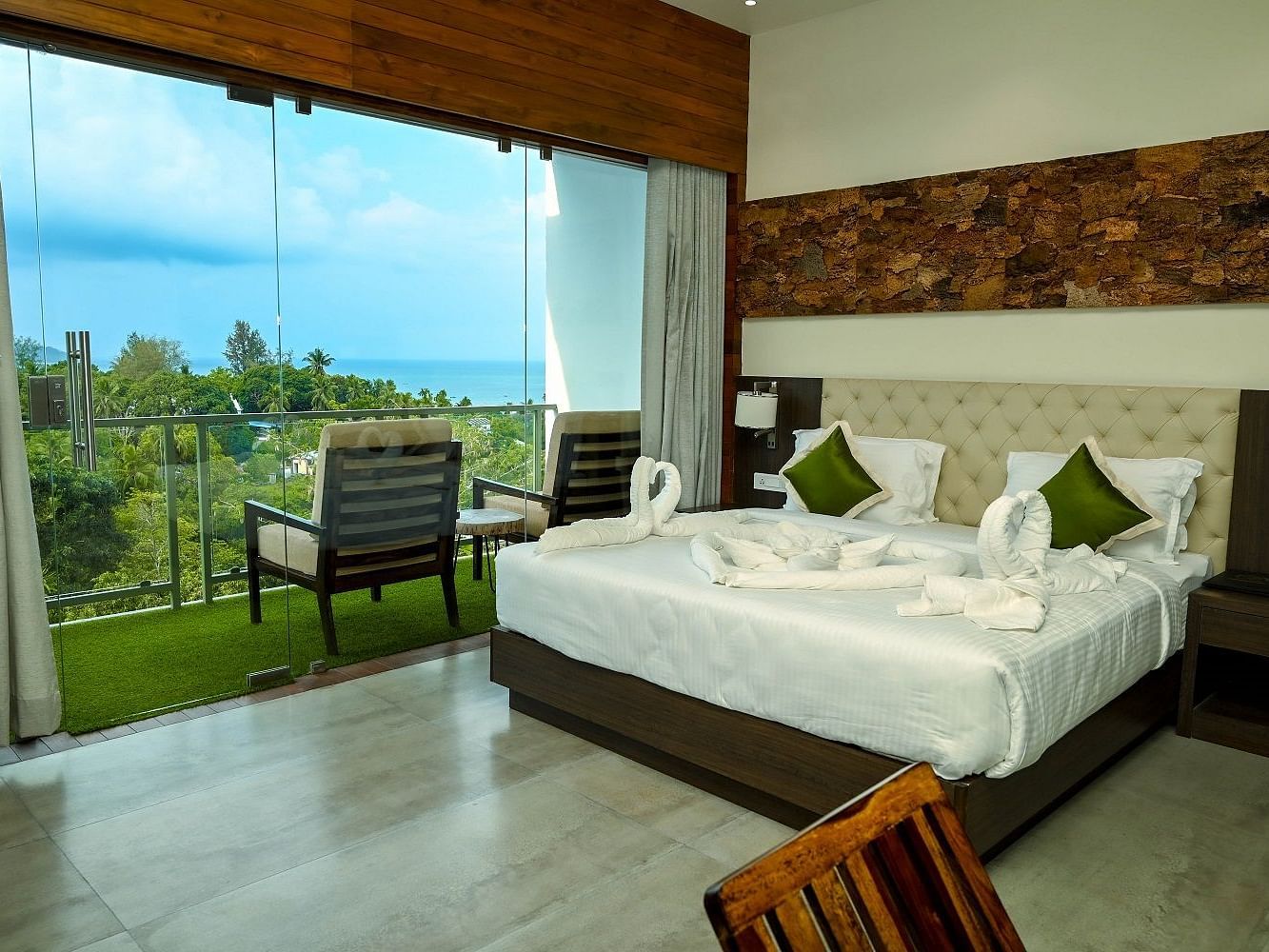A well-appointed room with a large bed, contemporary furniture, and expansive windows overlooking natural scenery - Sea Hills Hotels, Sri Vijayapuram (Port Blair)