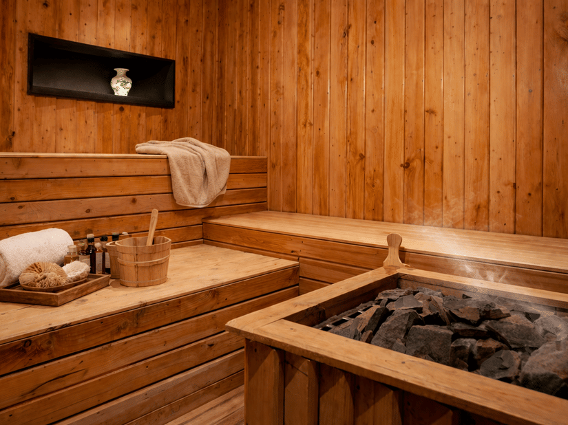 The room features light-colored wooden paneling on the walls and tiered wooden benches for seating  - Manor Sports & Wellness Hotel