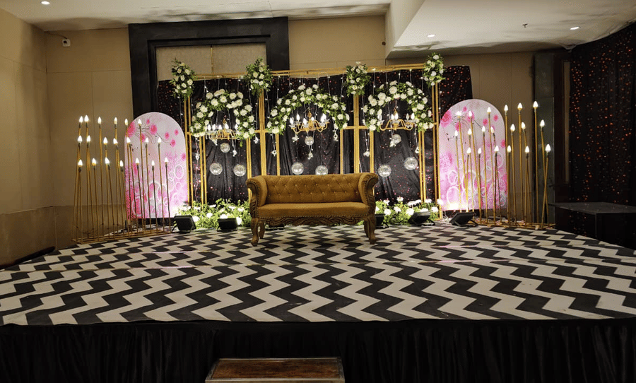 Banquet hall pre-function area with a floral stage backdrop, decorative seating arrangements, and an event setup at Ambrosia Sarovar Portico, Haridwar.