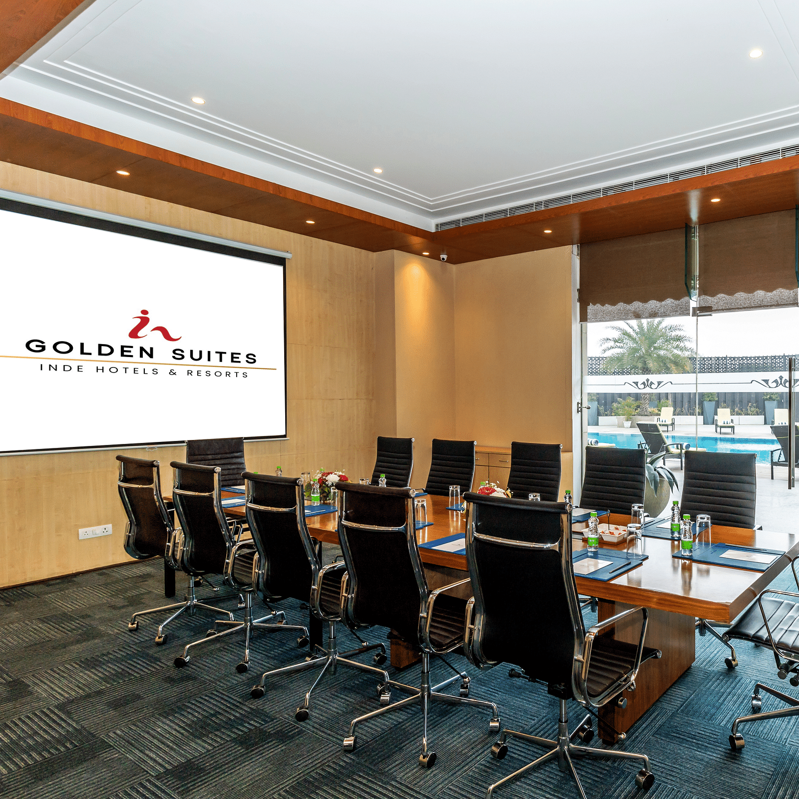 Boardroom with chairs round the table and a screen at Golden Suite