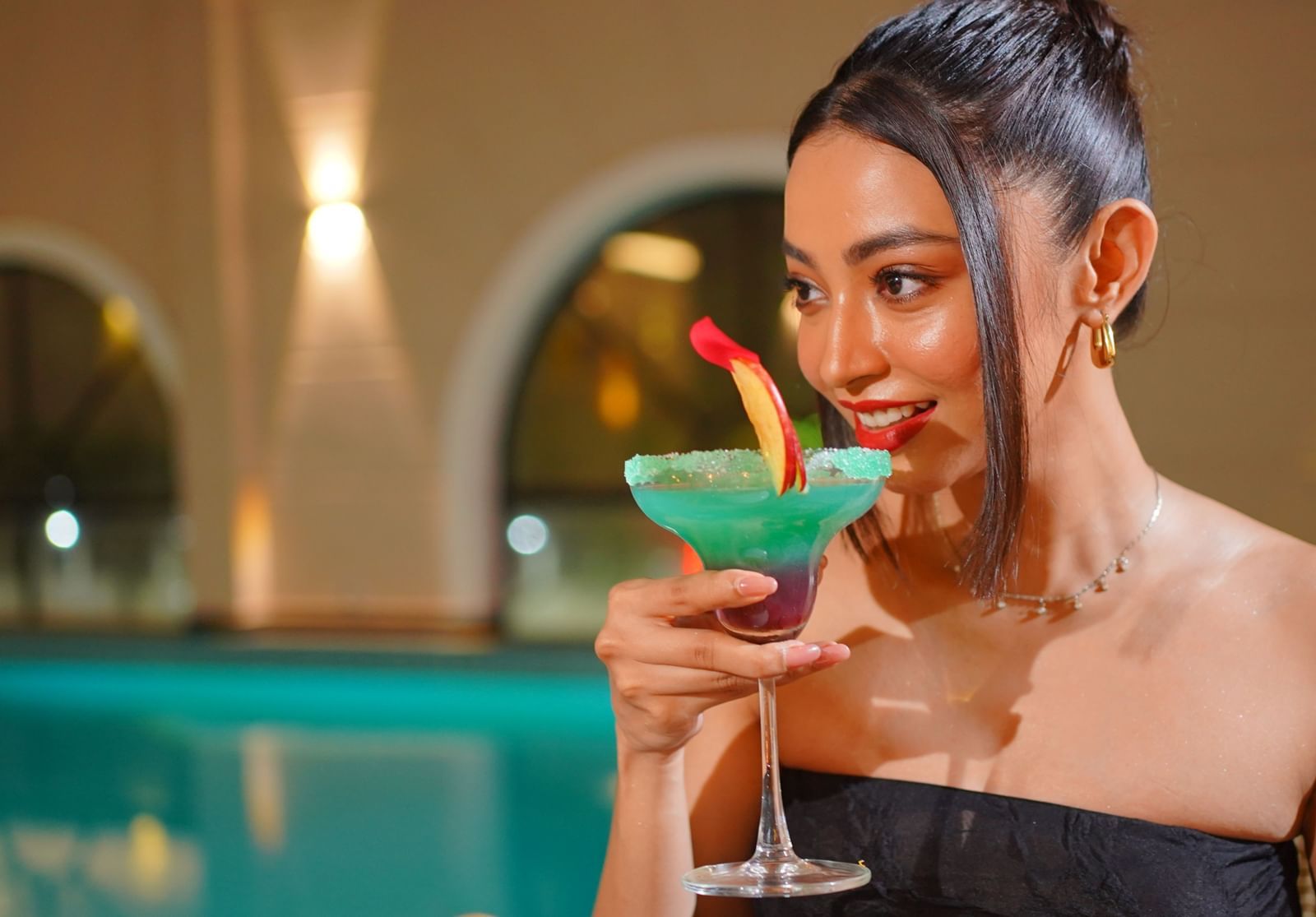 Close-up of a woman drinking a cocktail topped with a fruit peel - Polo Hotel Agartala