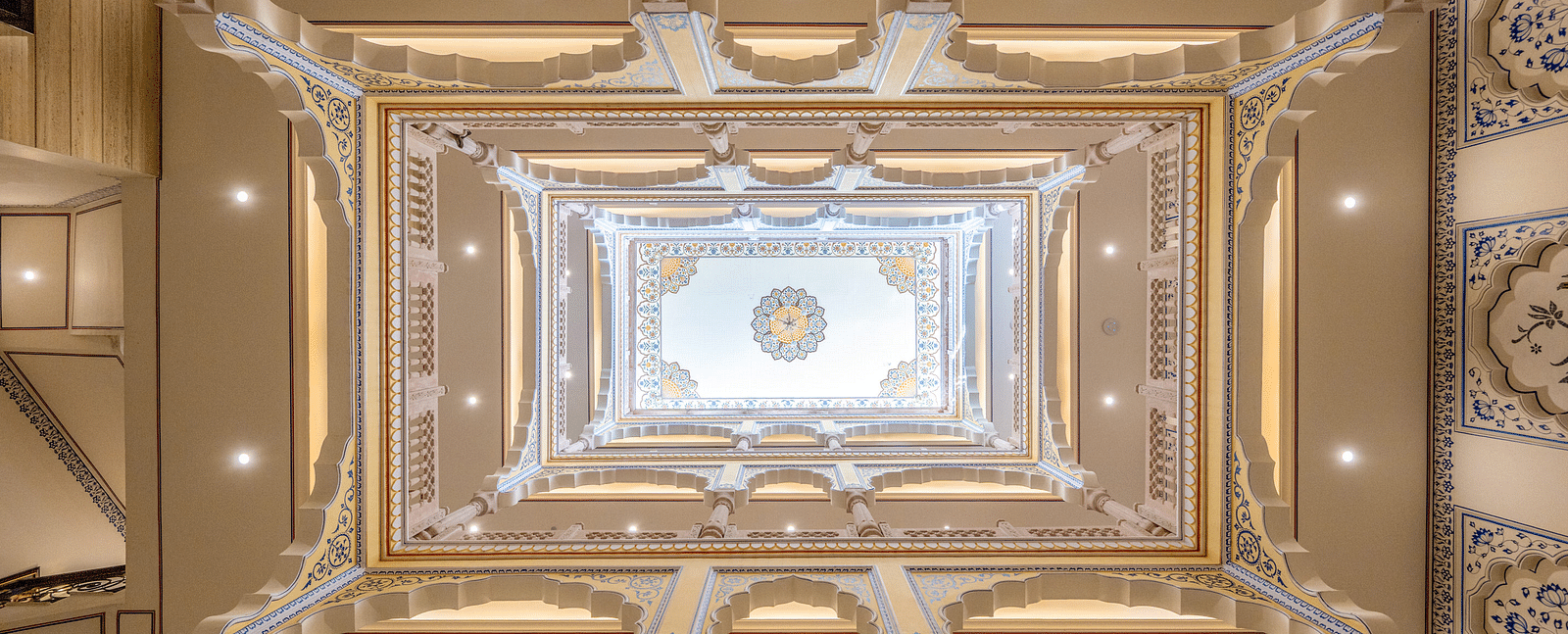 a beautiful atrium above the lobby of our hotel going four levels up with intricate paintings on the wall - Brij Castle, Jaipur