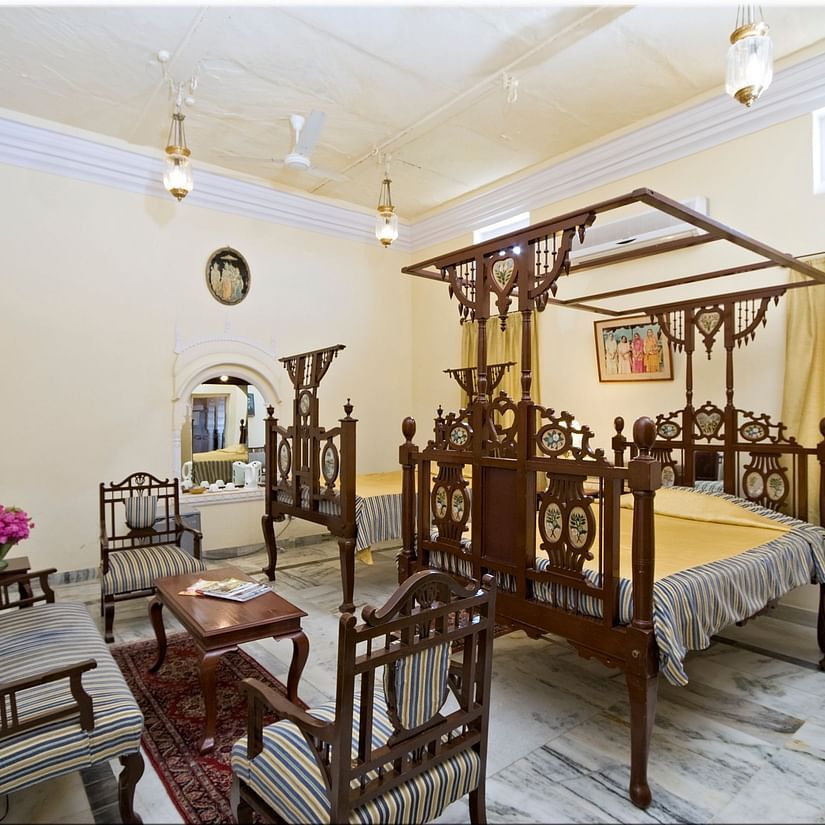 a bedroom with a sofa and a large bed with canopy covers - Hotel Castle Mandawa, Jhunjunu