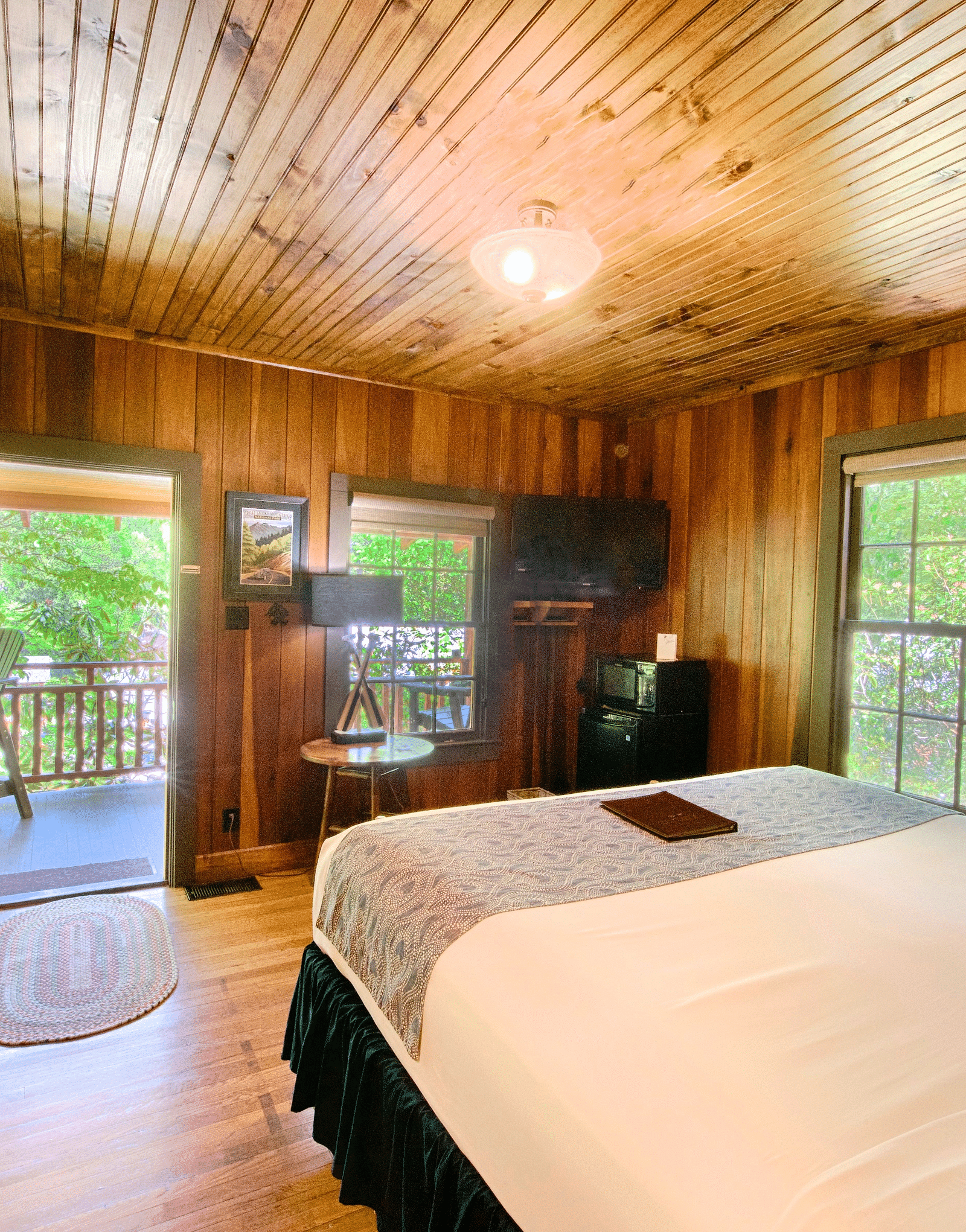 a beautiful image of a bedroom with wooden interiors with a double bed in the middle of the room - Historic Tapoco Lodge