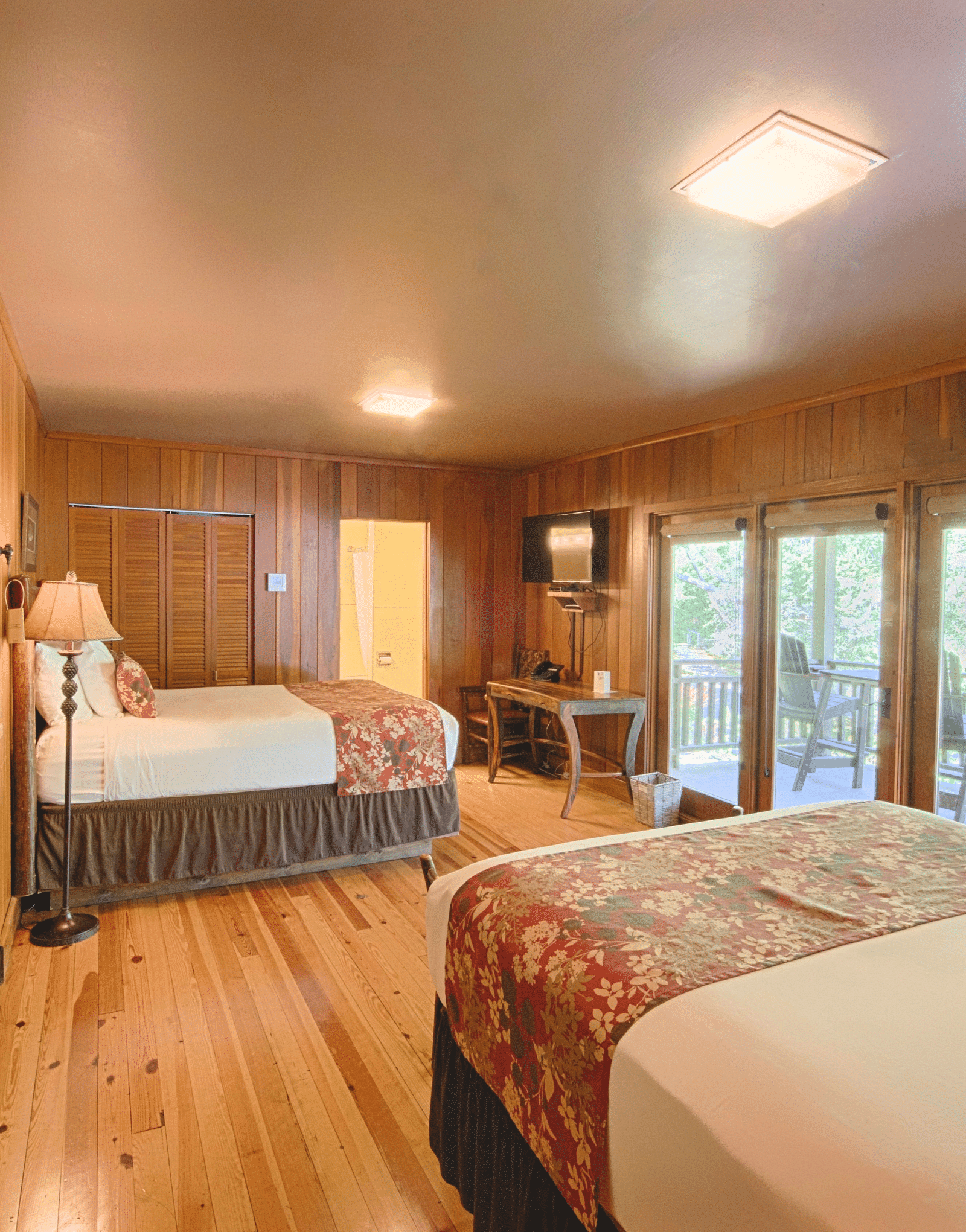 image of a bedroom with wooden flooring featuring huge french windows opening to a private porch - Historic Tapoco Lodge