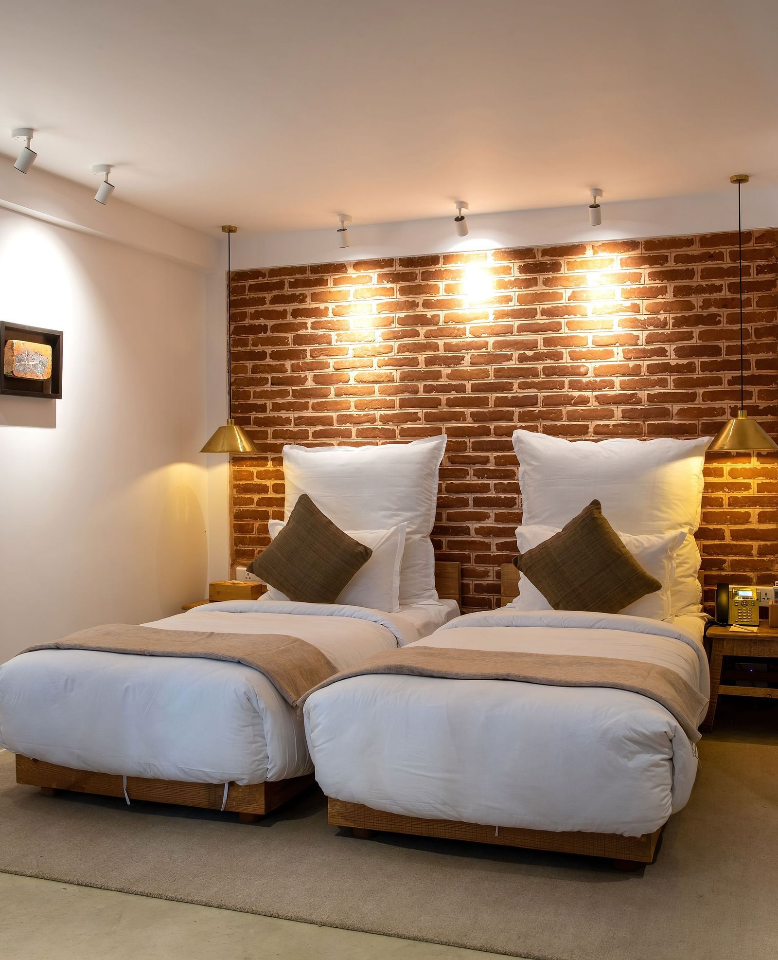 The room at The Nanee includes twin beds, bedside tables with lamps, and three pieces of artwork displayed on the wall.