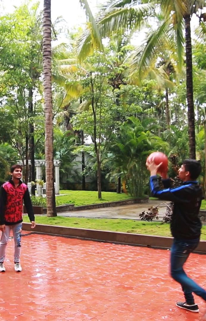 Image of four people playing basketball with trees in the background at Parampara Resort & Spa, Kushalnagar.