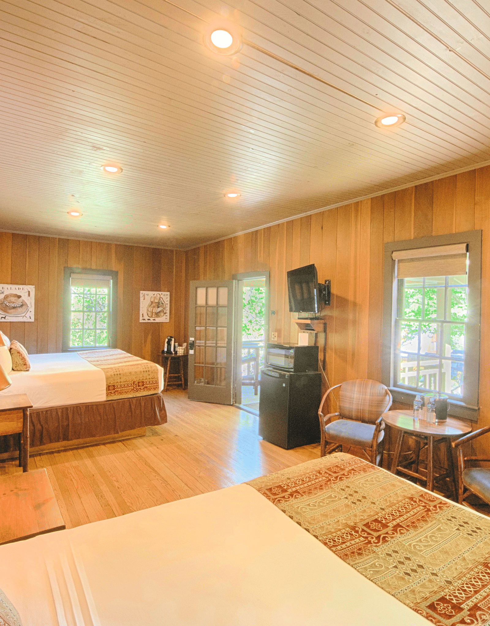 corner view image of a bedroom featuring two plush double beds with a coffee table in front of it - Historic Tapoco Lodge
