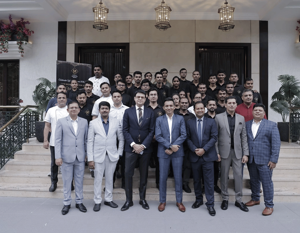 A group of people dressed in business formals gathered together in front of a hotel building.
