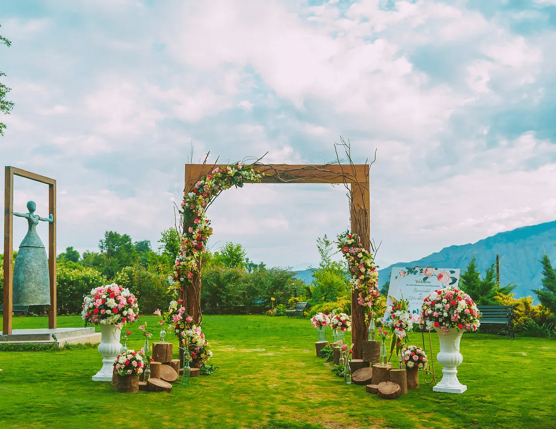 a wooden entrance with flowers decorated on it kept on the manicured grass - neer ganga Resorts