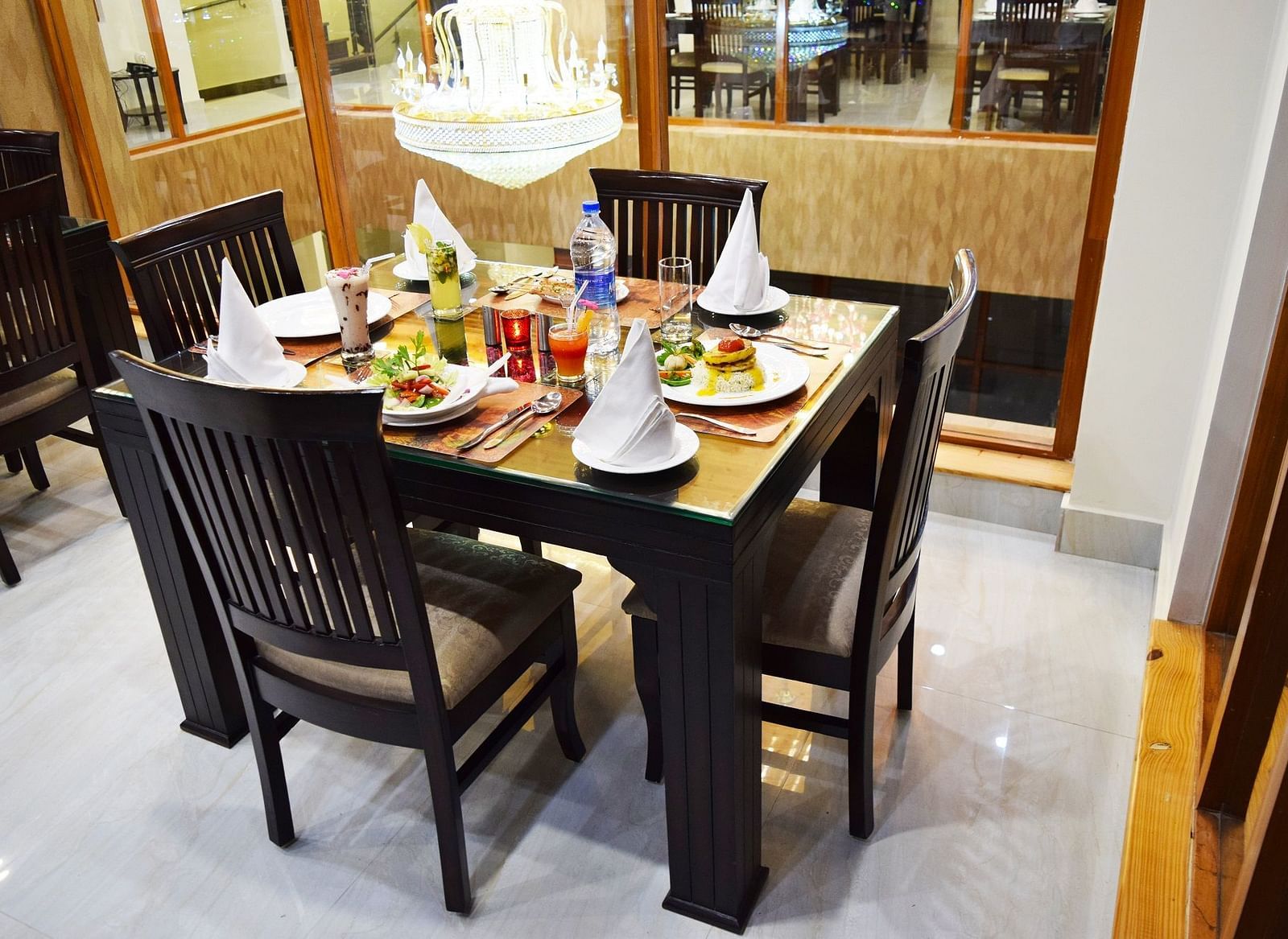 The image shows a dining table set for four people  | DLS Serenity Resort and Spa