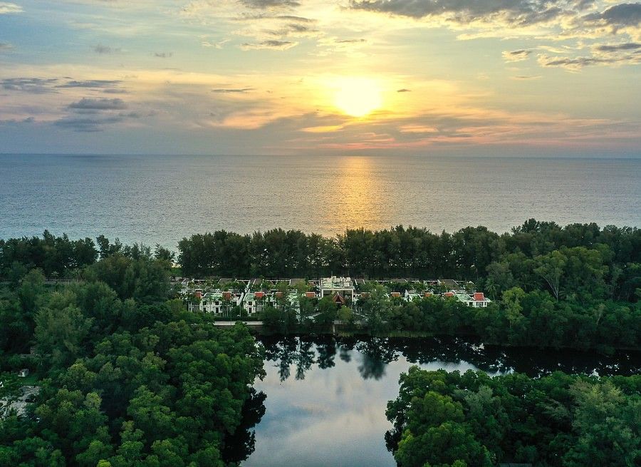 alt-text image of a serene sun setting in the calm waters - maikhao dream villa and spa, phuket