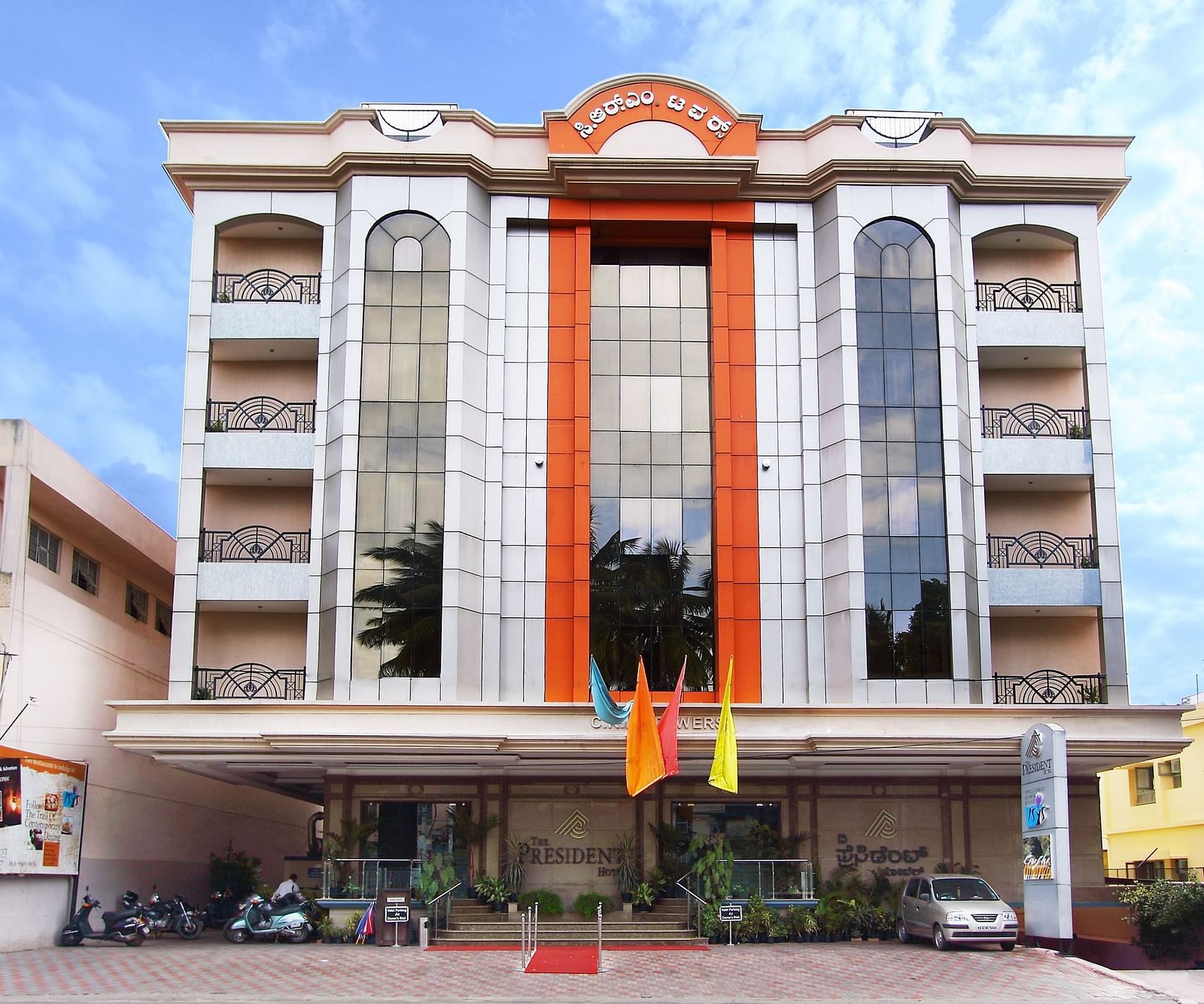 Facade of The President Hotel Jayanagar, Bangalore with striking red accents and a majestic entrance, showcasing a blend of traditional and contemporary architecture 