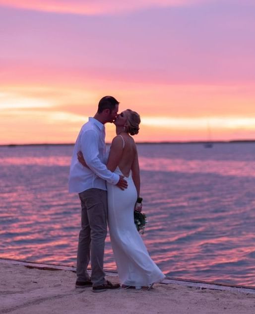 Bride and groom embracing by the ocean at sunset at Casa Morada.