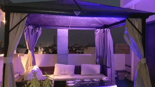 A luxurious outdoor dining setup with purple ambient lighting and elegant canopy seating at the a Family Restaurant (Varanasi) - Hotel Uday Palace.