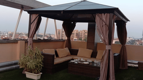 An elegant rooftop dining area with canopy seating and city views at a Restaurant for Couples in Varanasi -  Hotel Uday Palace.