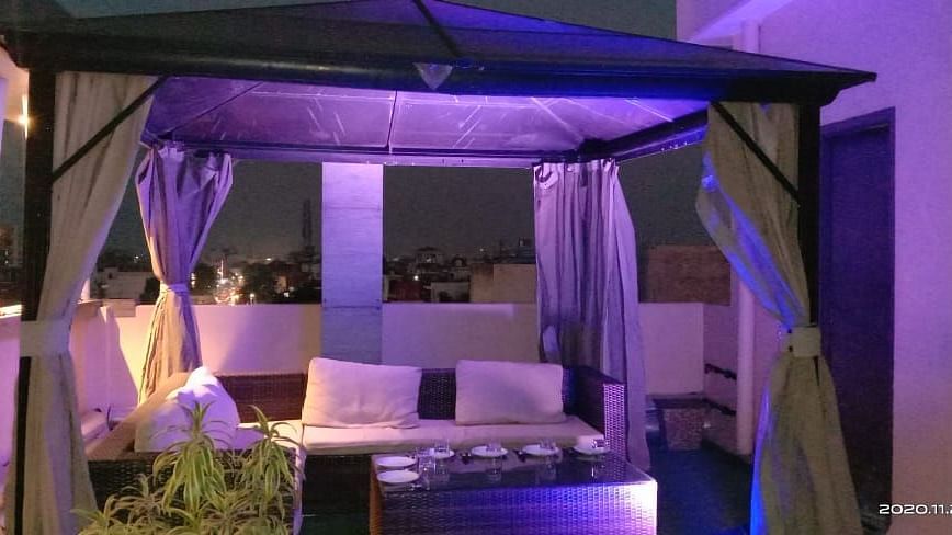 Tables and chairs are arranged below the curtain-draped top and pillars at Hotel Uday Palace.