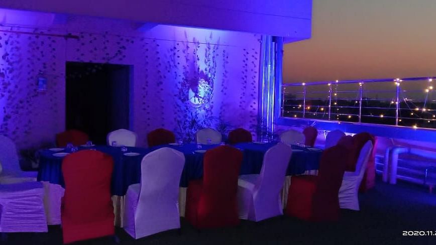 The event space at Hotel Uday Palace features cool-themed lighting with tables and chairs arranged in an open setting.
