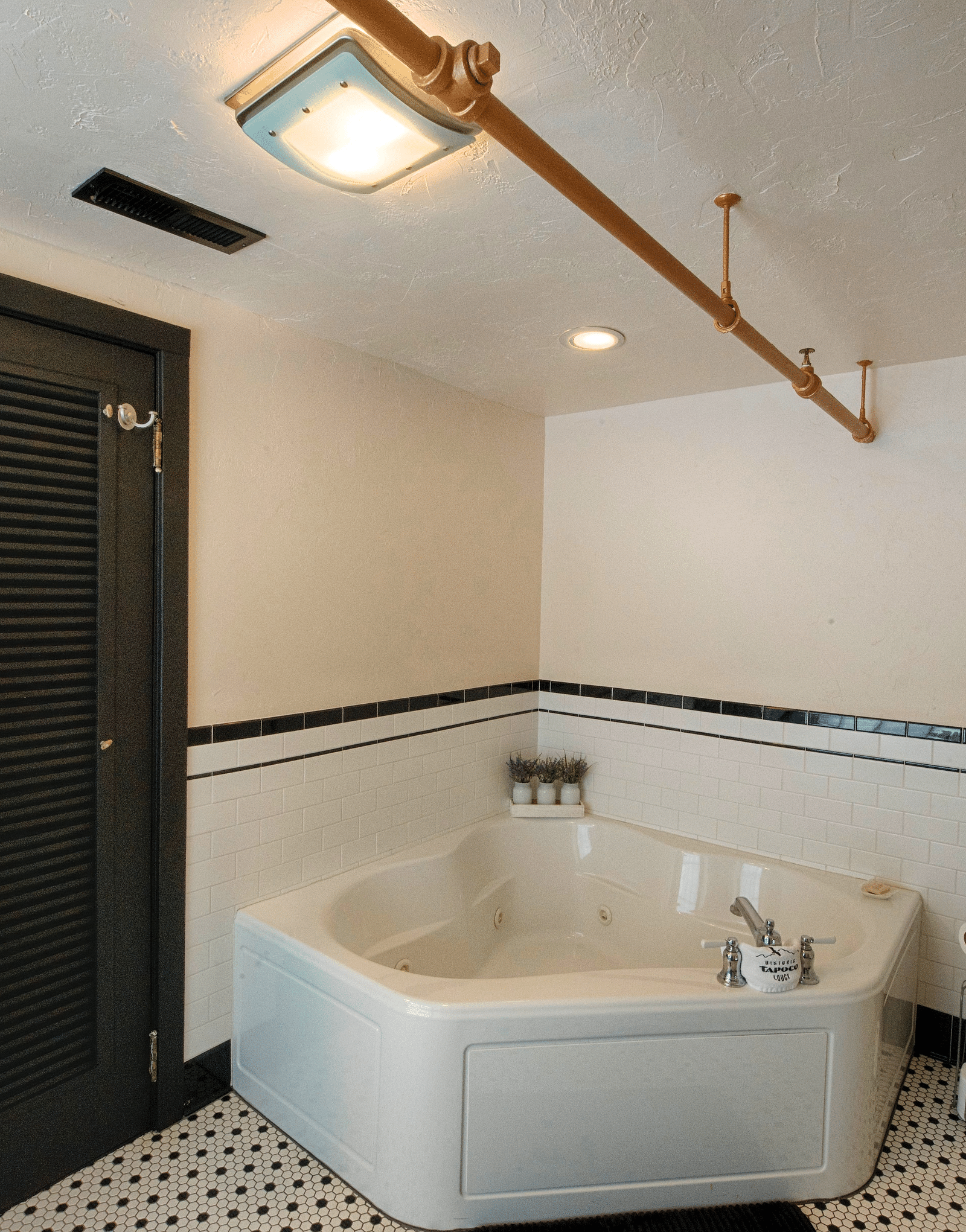 a luxurious bathroom featuring a full size bathtub beside a huge black door with a bathrobe hanging over it - Historic Tapoco Lodge