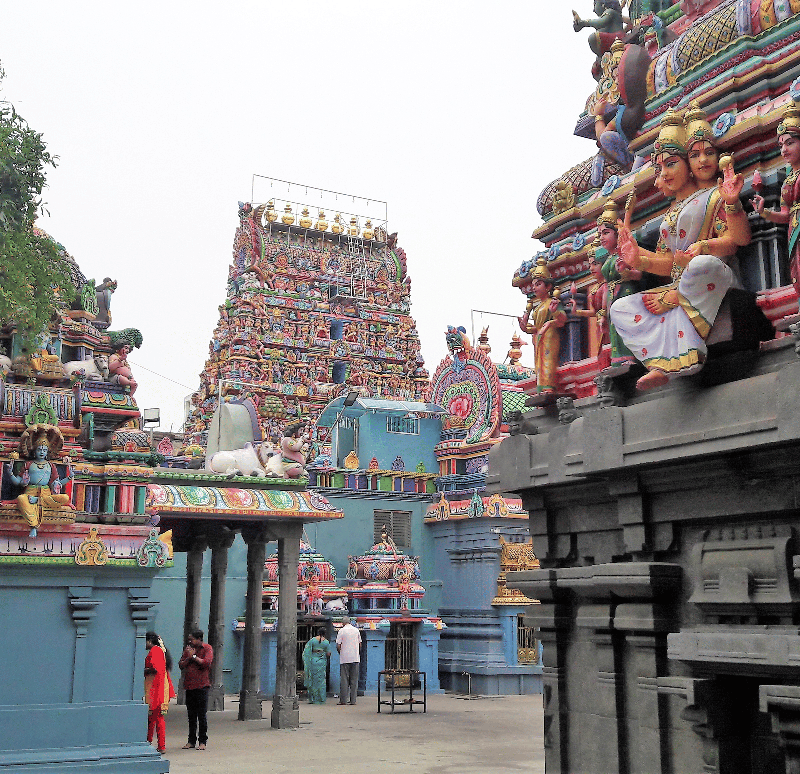 The colourful Vedapureeswarar Temple in Pondicherry featuring vibrant statues of Hindu deities along its detailed towers and stone walls.