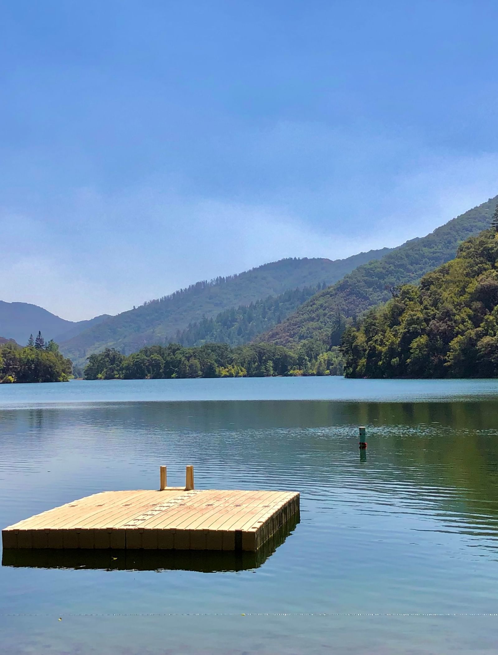 A small platform located in the midst of a waterbody that is surrounded by forested hills near Tallman Hotel.
