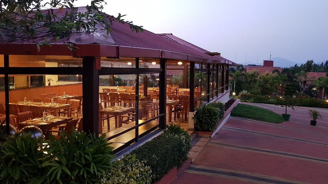 View from outdoor area of a restaurant in a wooden structure and lush greenery | Sheesham Restaurant | Woodstock Resorts, Coorg