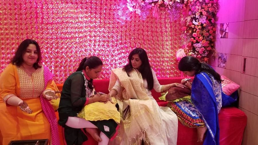 Two women applying mehendi on a ladys hand at at The Oriental Residency