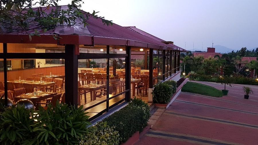 View from outdoor area of a restaurant in a wooden structure and lush greenery | Sheesham Restaurant | Woodstock Resorts, Coorg