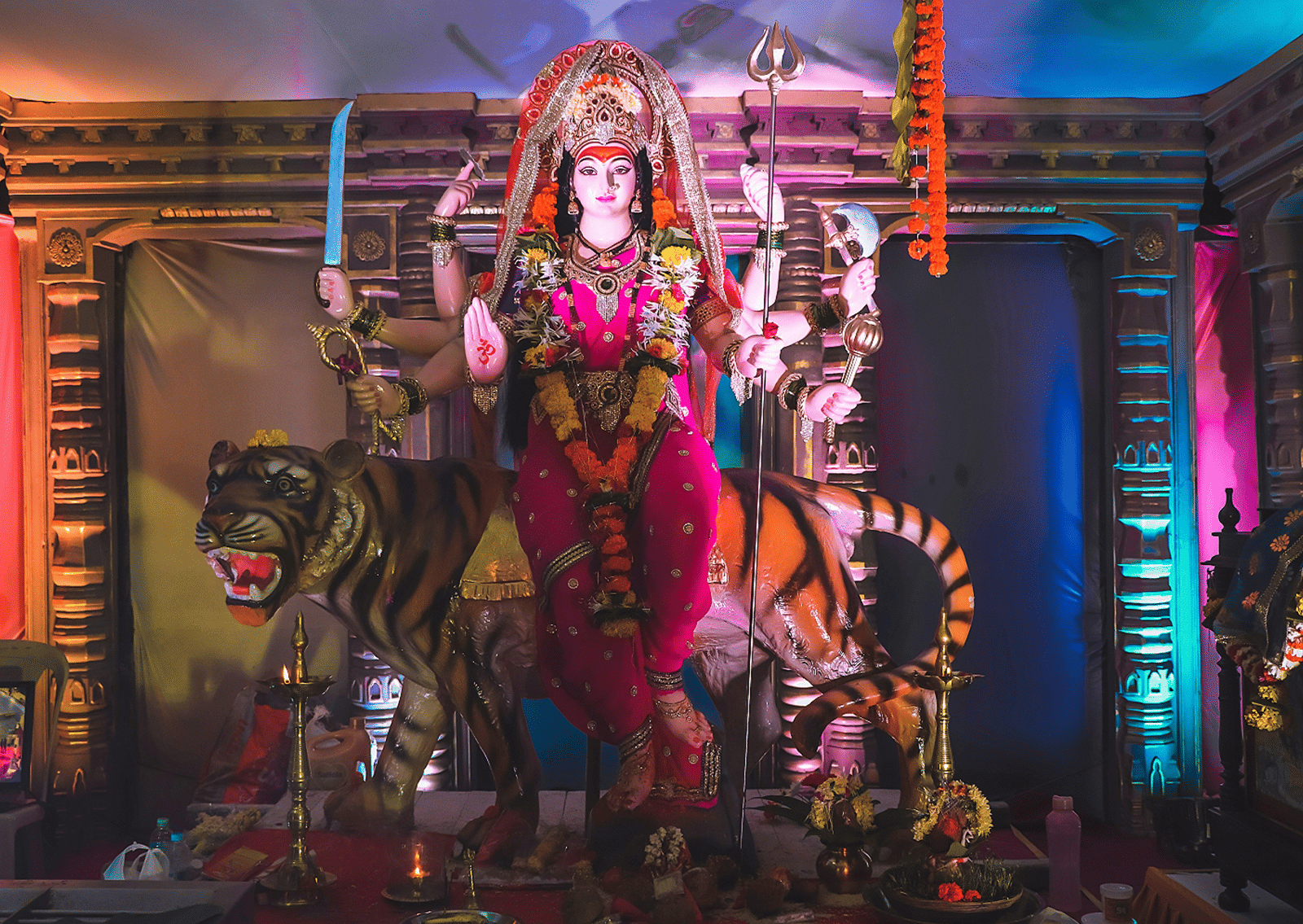 A brightly illuminated idol of Goddess Durga seated on a tiger inside a Durga pandal Indore.