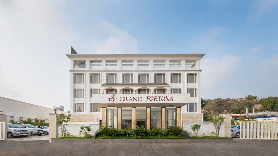 The front exterior of the TGI Grand Fortuna hotel with parked cars and a clear blue sky above - TGI Grand Fortuna, Hosur
