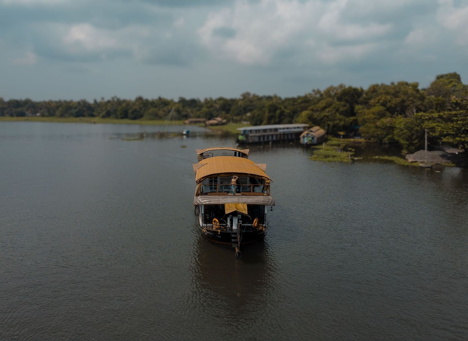A cruise sailing across the Vembanad Lake with lush greenery in the background - BluSalzz Villas - Muhamma Resort, Alleppey